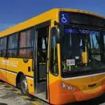 Un colectivo amarillo y naranja estacionado en un estacionamiento.