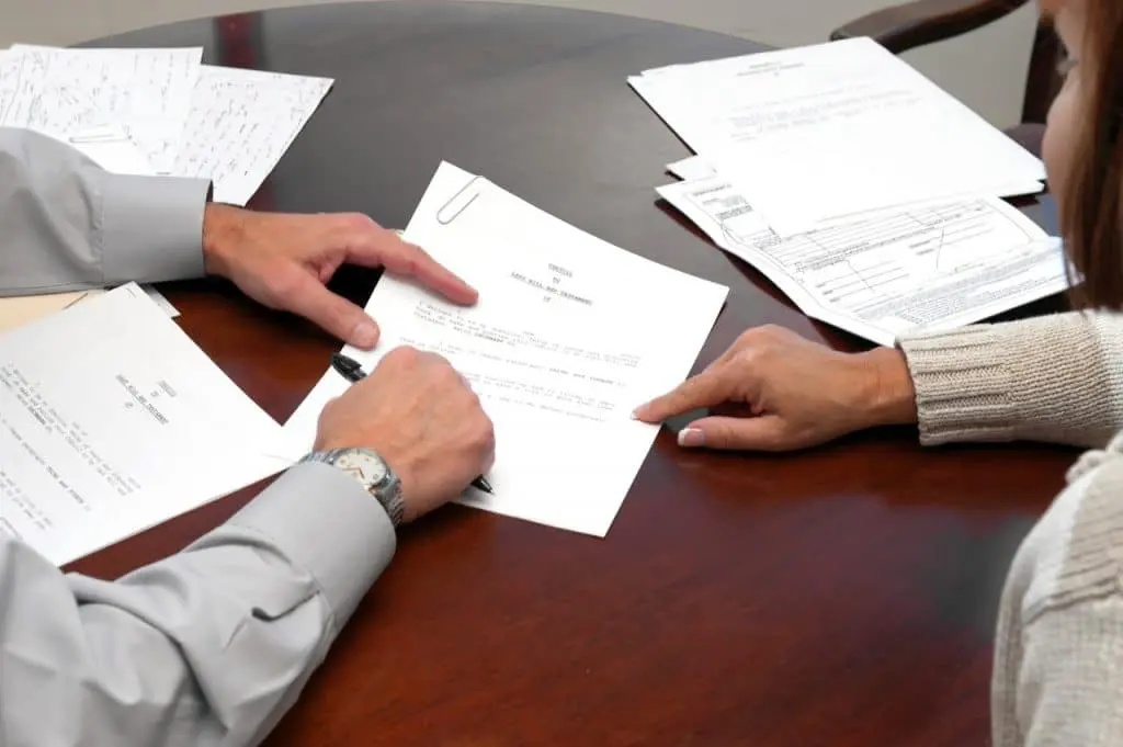 Un hombre y una mujer firmando documentos en una mesa para el cpc.