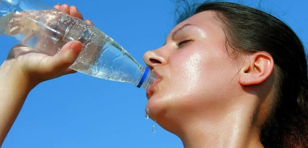 Consejos para evitar golpes de calor en córdoba Una mujer en córdoba bebiendo agua de una botella, siguiendo consejos para prevenir golpes de calor.