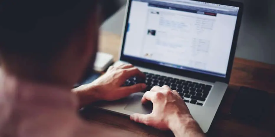 Cómo hacer denuncias de delitos menores por internet Un hombre que utiliza internet en su computadora portátil para realizar informes sobre delitos menores.