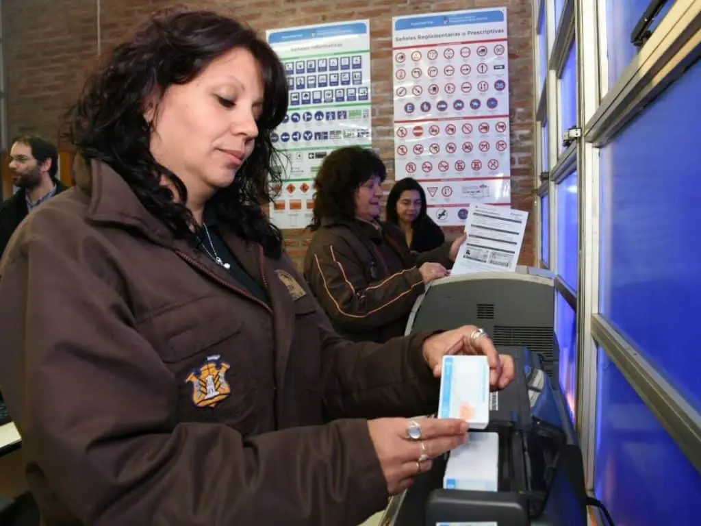 Una mujer introduce billetes de córdoba en una máquina expendedora.