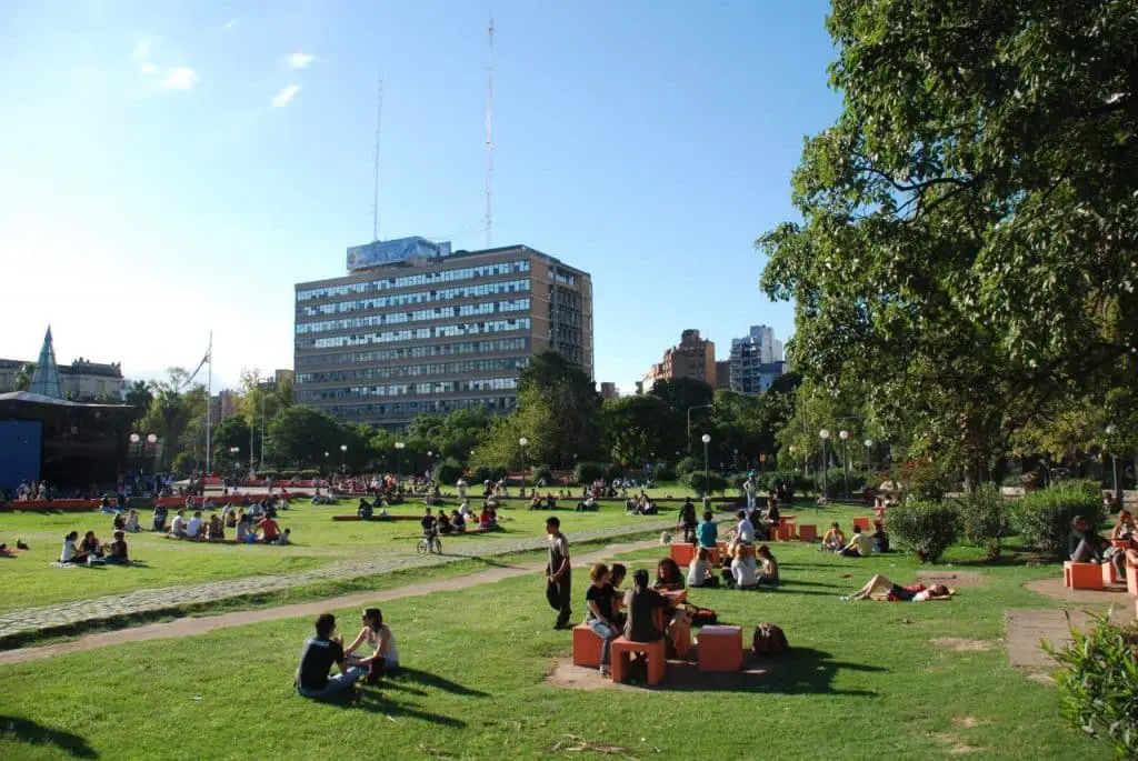 Un grupo de personas sentadas en un parque de córdoba disfrutando del clima de octubre y participando en visitas guiadas.