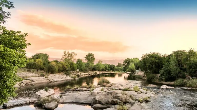 Guía para planificar viajes económicos desde córdoba a distintos destinos Paisaje de traslasierra en córdoba con río y montañas al atardecer