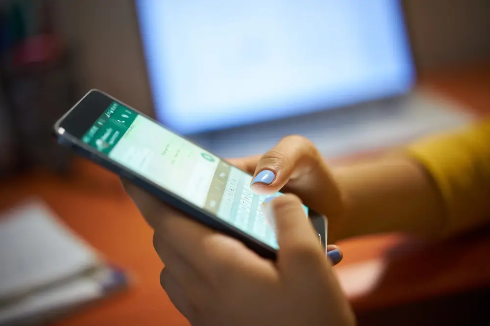 Persona usando whatsapp en un teléfono celular para seguir el canal de info de córdoba