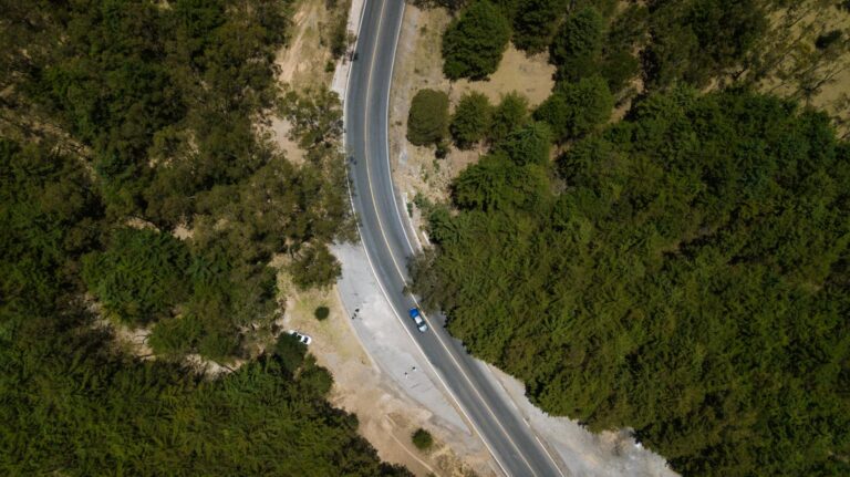 Aerial photo of asphalt road running through forest