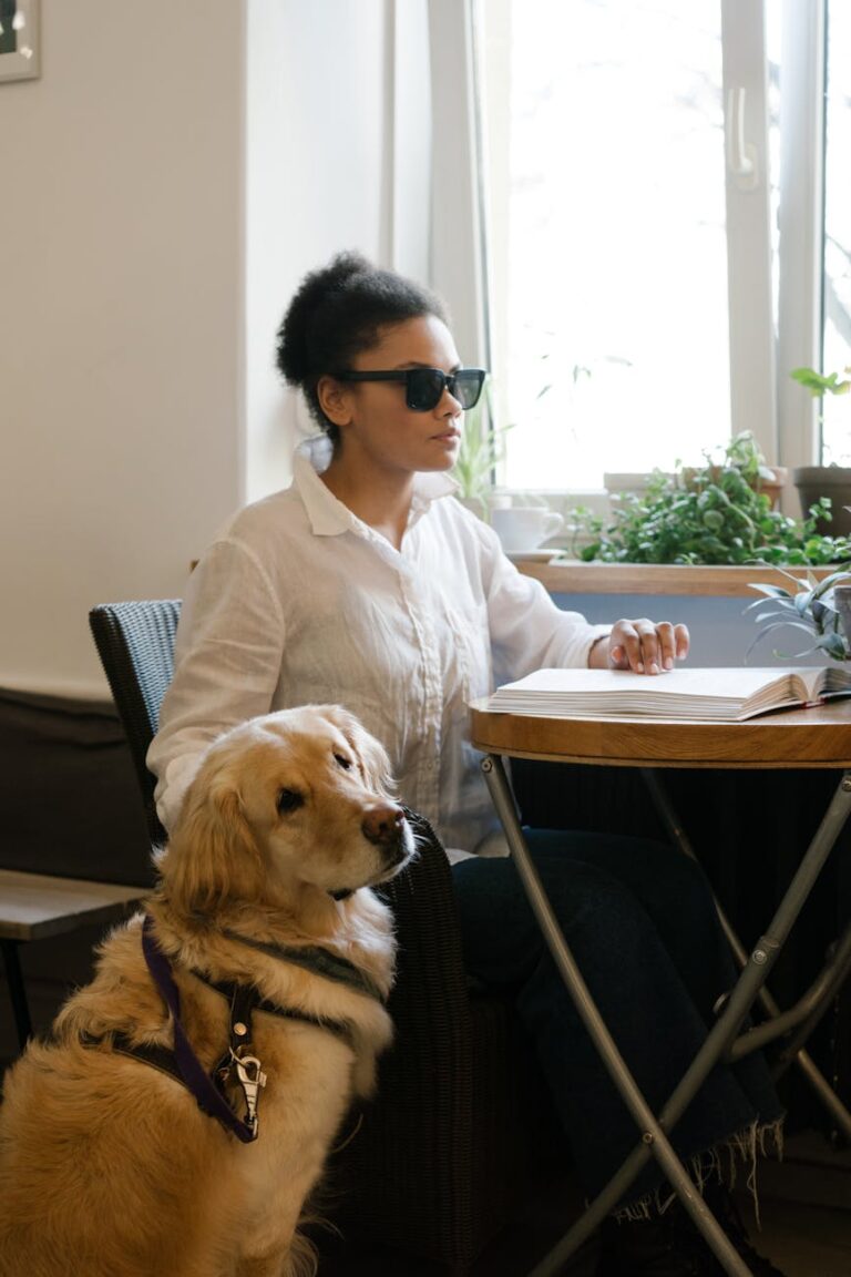 A woman reading a book beside her guide dog