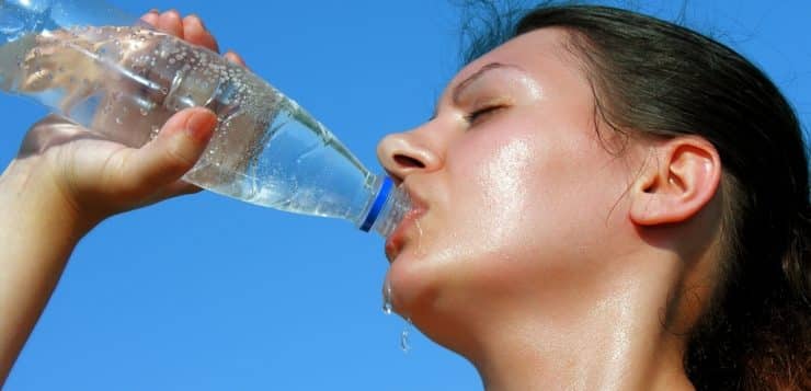 Una mujer en Córdoba bebiendo agua de una botella, siguiendo consejos para prevenir golpes de calor.