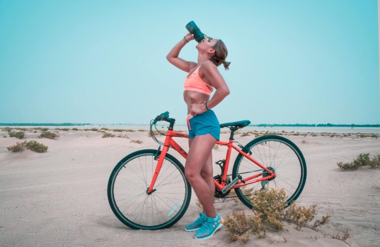Woman drinking on black tumbler while looking up and placing her left hand on waist